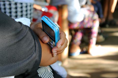 A person in the Philippines holds a cell phone in their hand. © 2015 David Batcheck