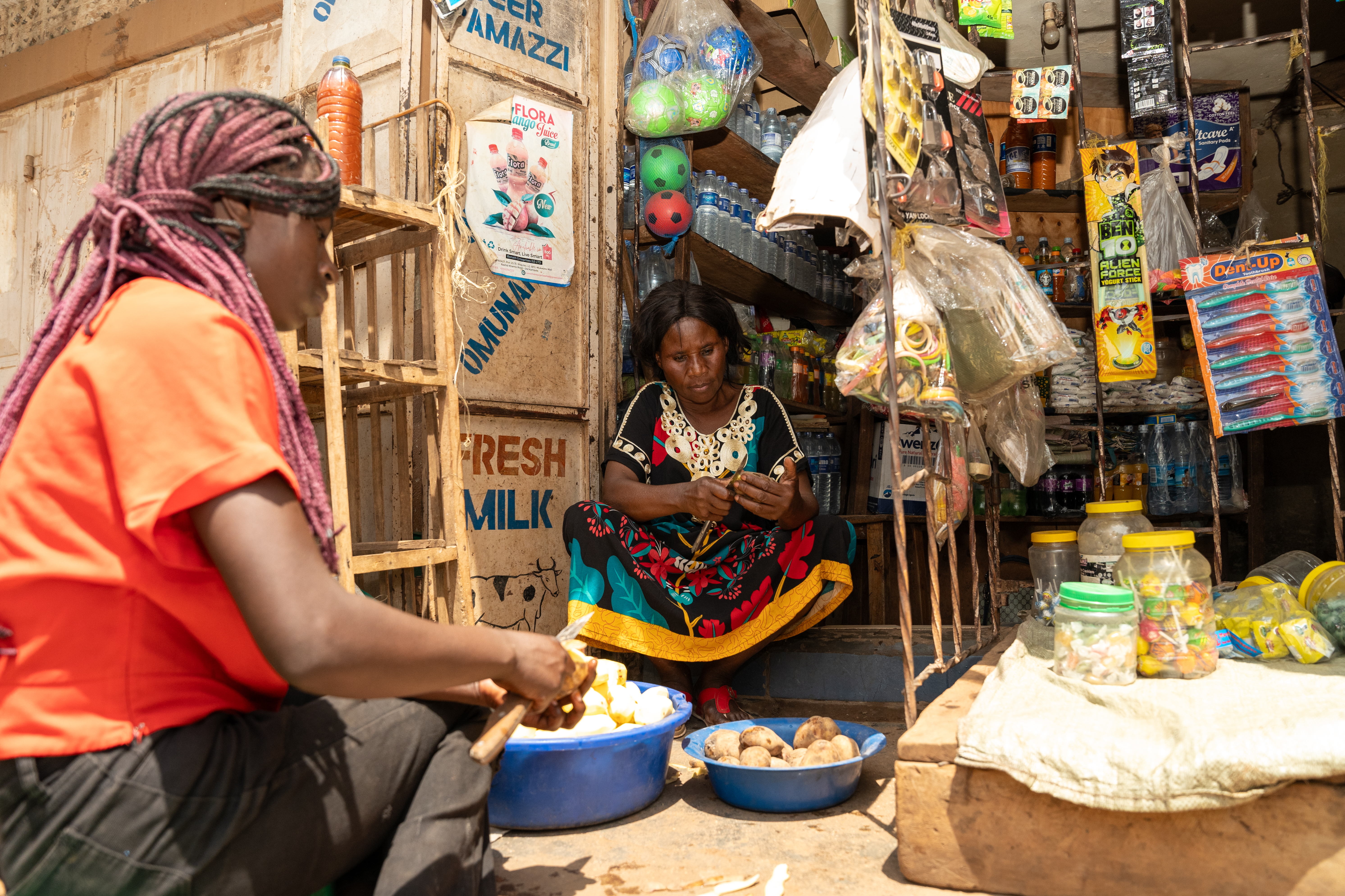 February 12, 2025, Kampala, Uganda. Jose Kahindo (right) and her niece peeling Irish potatoes - one of fastest-selling items at her shop. Kahindo received a business grant from the IRC & IKEA Foundation’s Re:BUiLD program