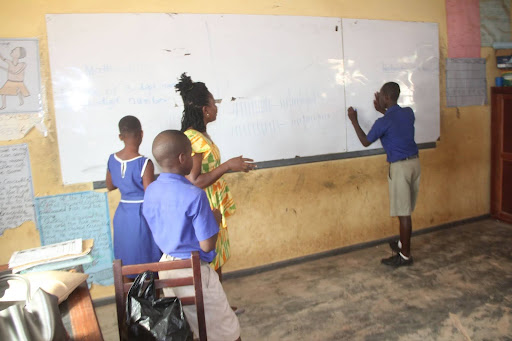 A teacher with students in a classroom, photographed during an IPA study in Ghana. ©2019 IPA