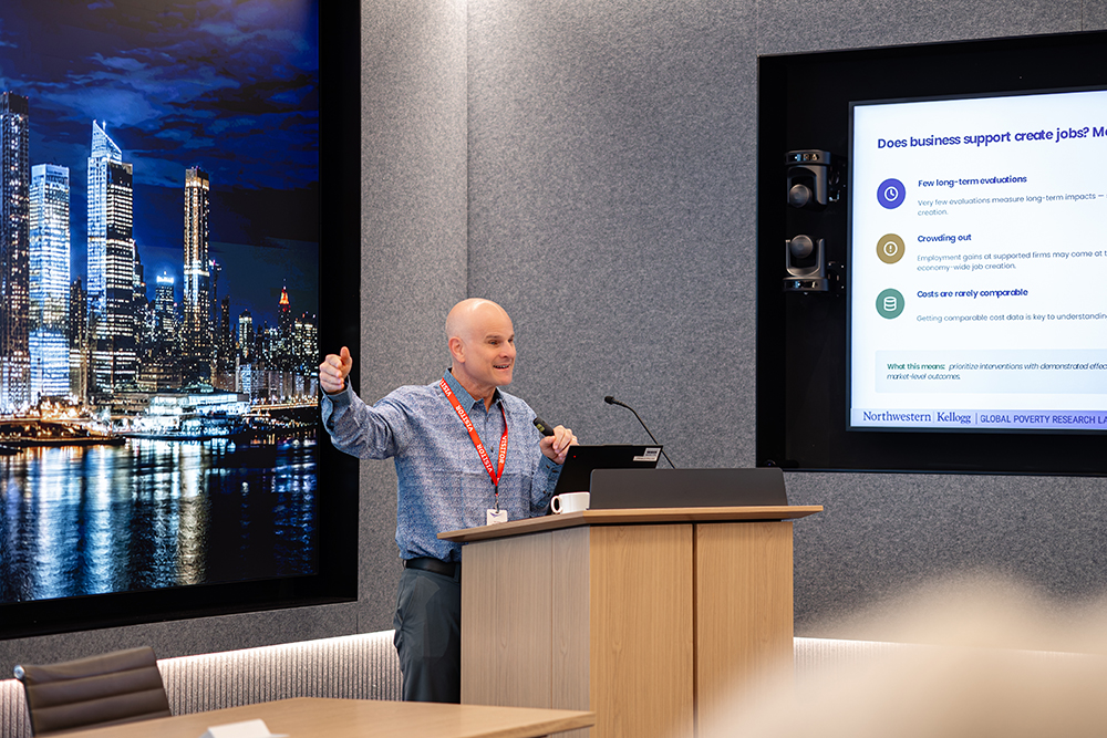 Dean standing at the podium presenting his slides on a projector screen
