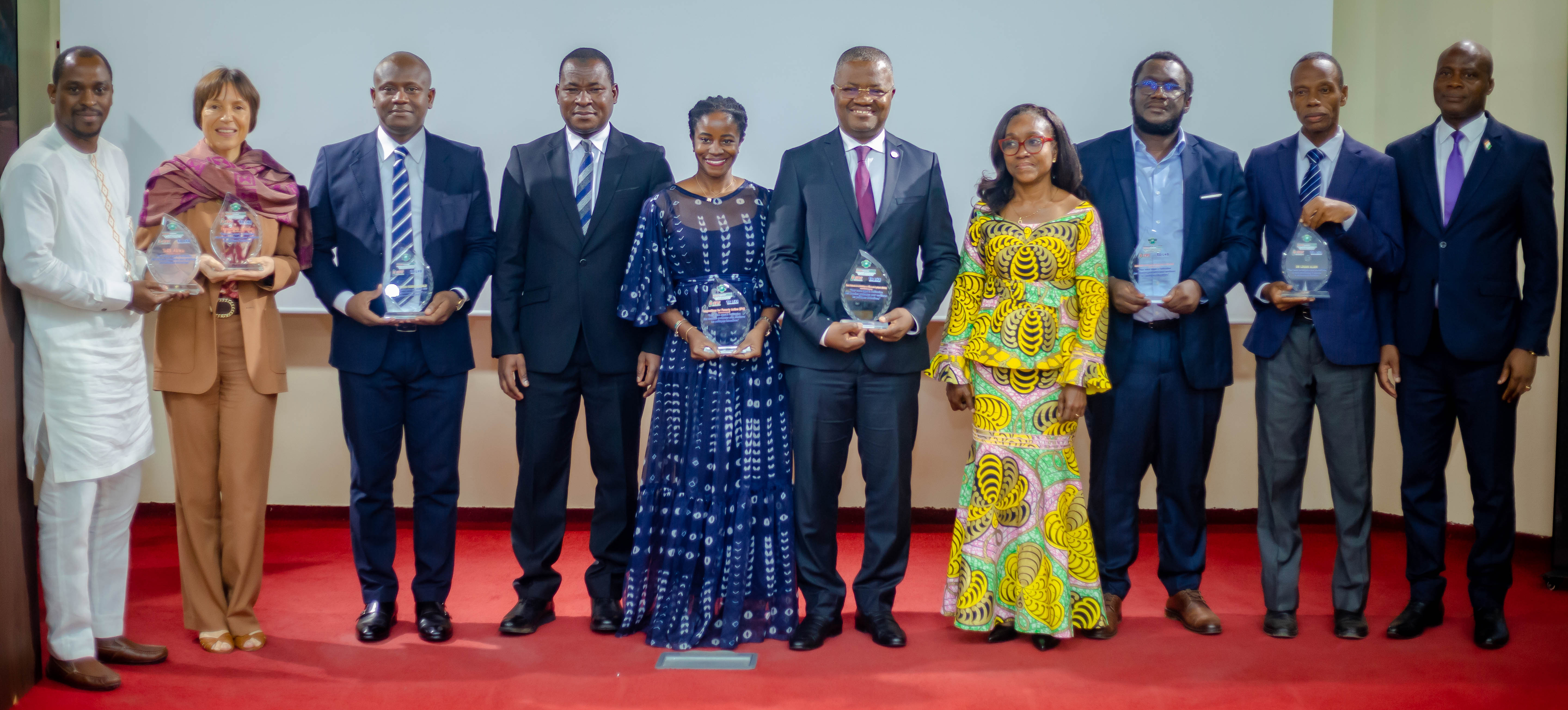 Representatives from IPA and MENAET standing on a stage while holding awards in their hands