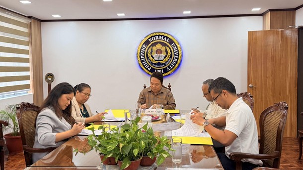 Event attendees sitting at a table reviewing and signing the MOU documents