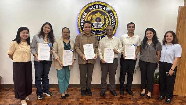 Signatories of the MOU smiling while some of them hold paper copies of the signed MOU