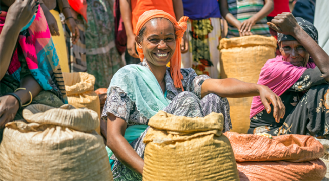 Photo from MAGNET website of a woman smiling while sitting in an outdoor market