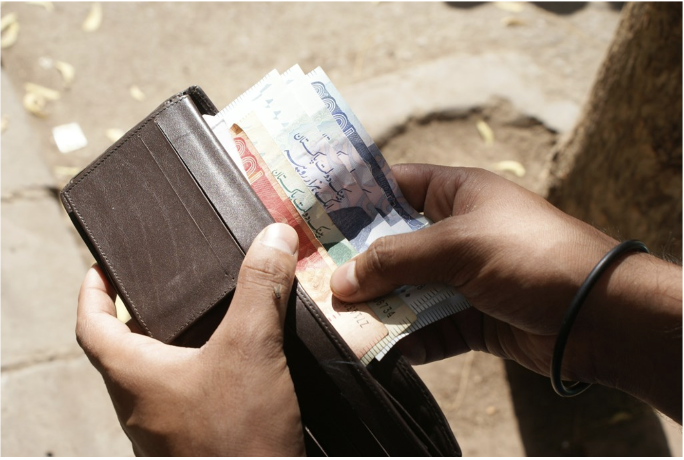 An individual counts Pakistani Rupee in Karachi, Pakistan (Photo by Zeeshan Tejani on Unsplash)