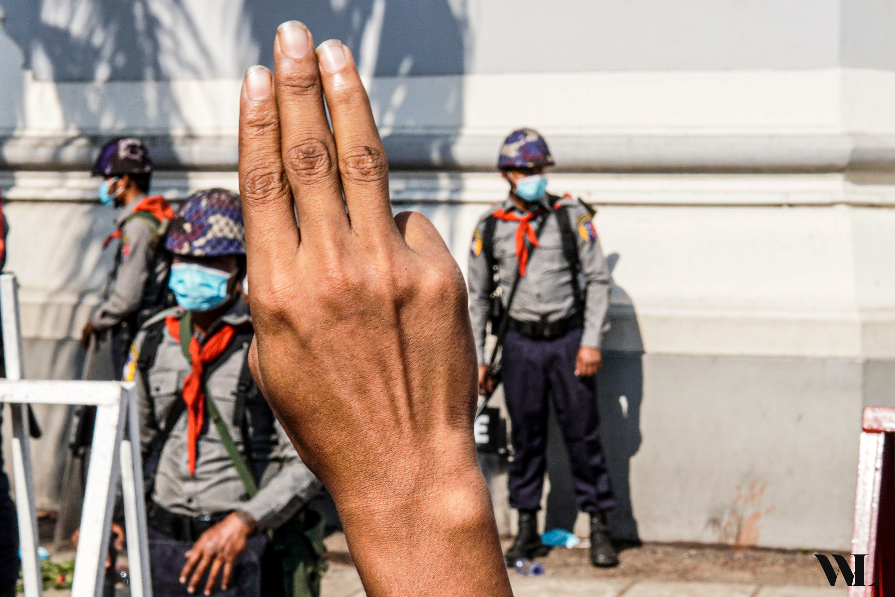 Protestor displays a pro-democracy salute in front of police officers in Yangon, Myanmar.