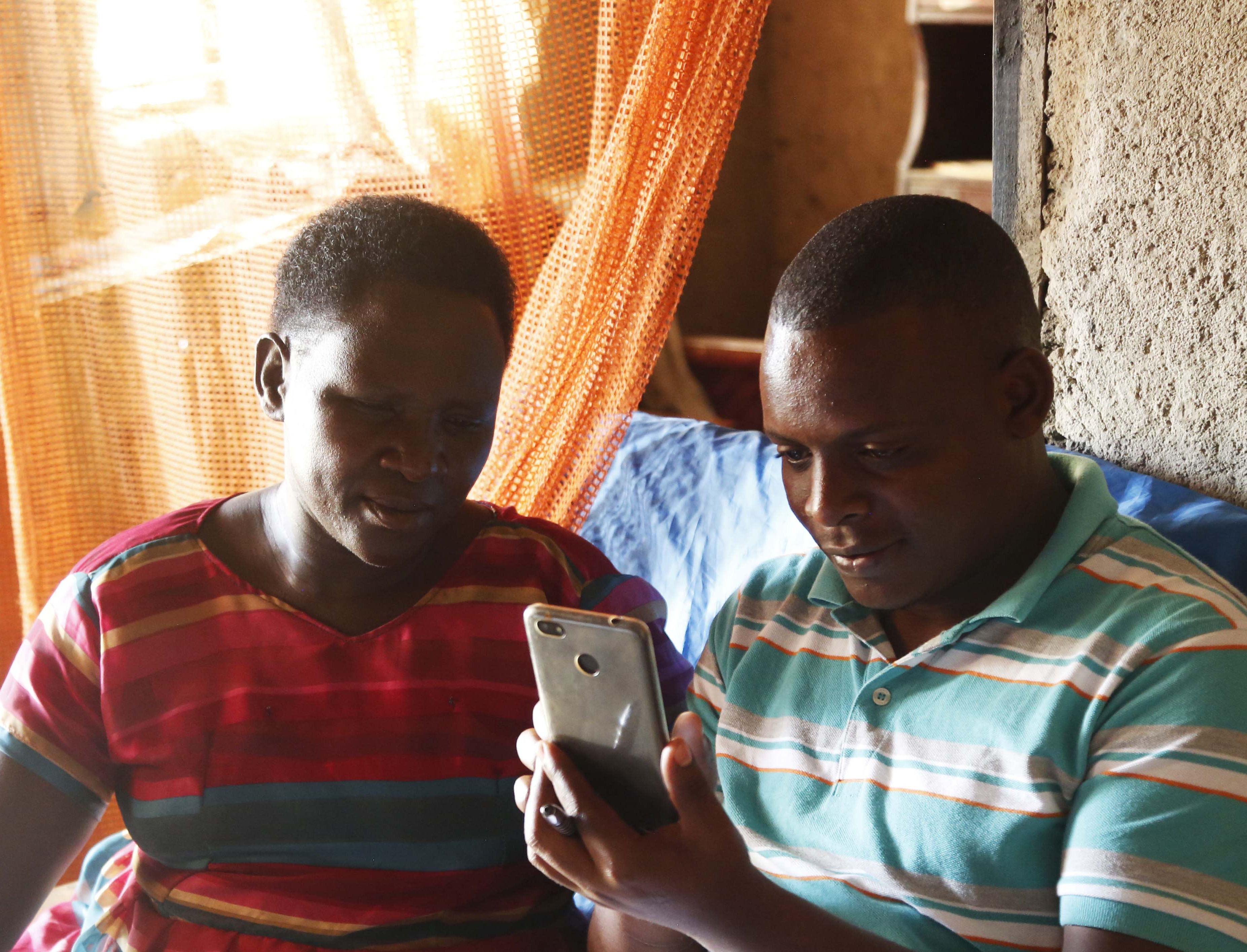 An IPA enumerator (right) shows a faith leader how to use a smartphone for the Becoming One program. © 2018 Aude Guerrucci