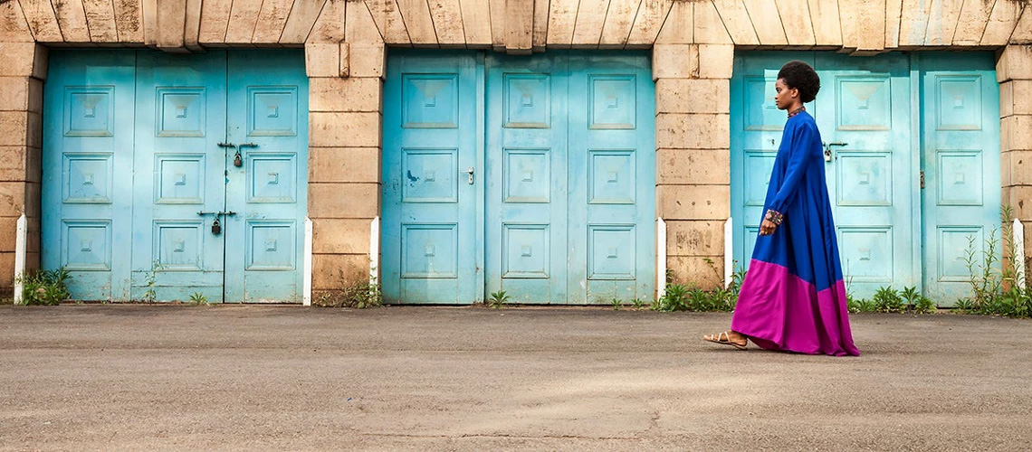 Photo of a woman walking on a street in front of three doors - from blog post on World Bank website