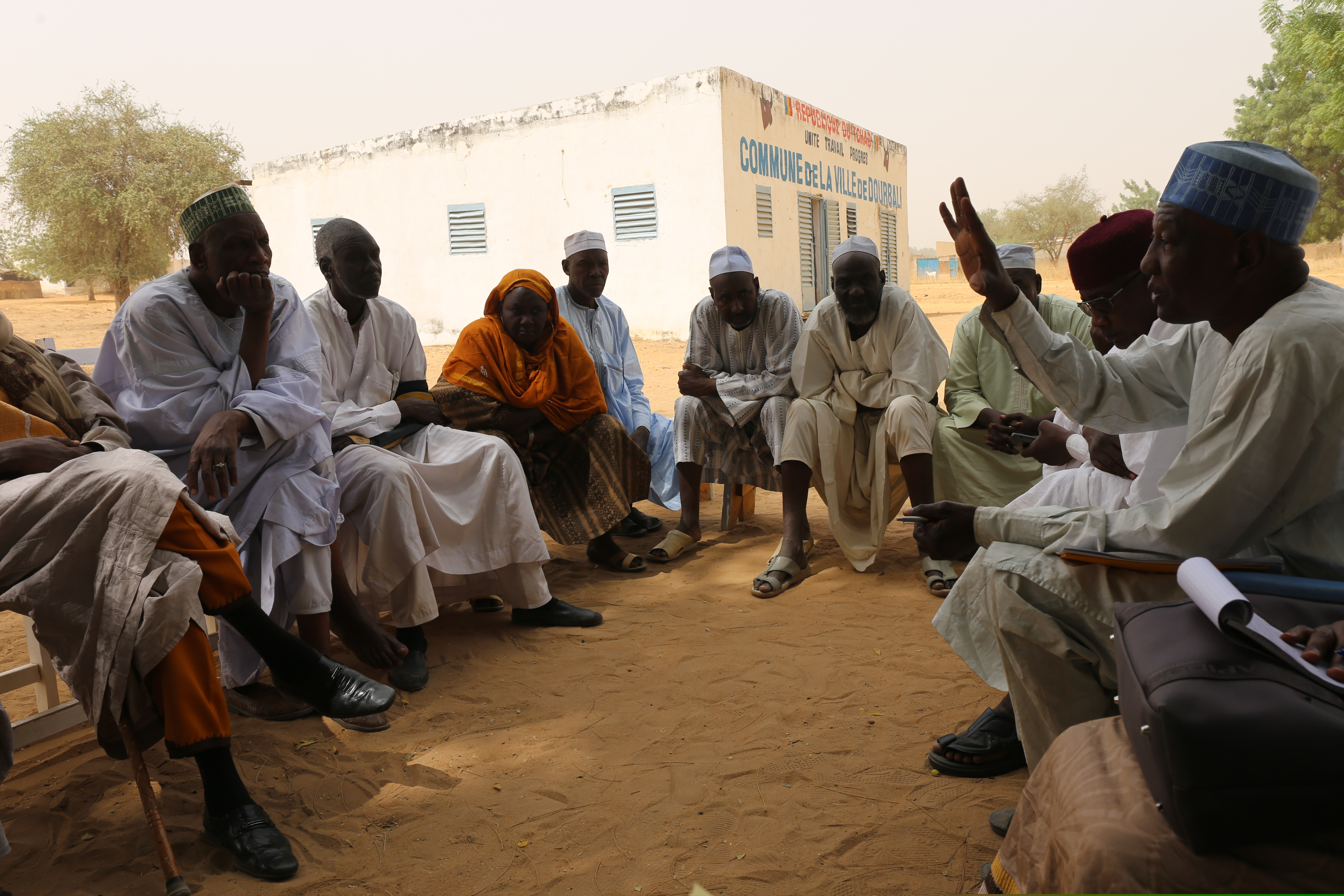 A group of men and women discussing during a village meeting.