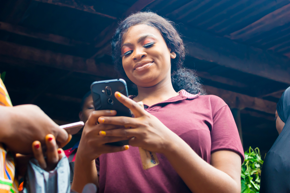 A woman empowers others by teaching mobile banking. © Wazzkii, from Shutterstock