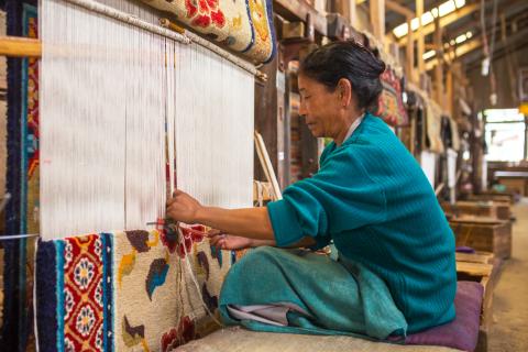 Une femme tibétaine travaille comme tisserande dans l'atelier de tapis du Centre d'entraide pour les réfugiés tibétains à Darjeeling, en Inde. © 2017 Shutterstock / Voyages Mazur