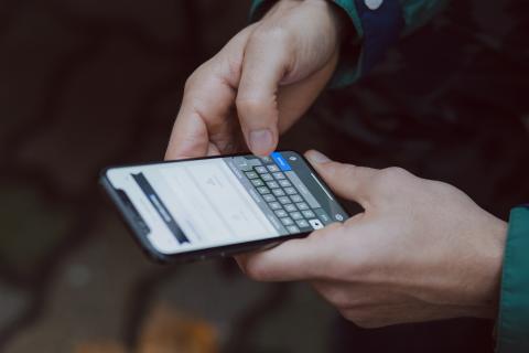 Une personne tenant un téléphone portable. © 2018 freestocks sur Unsplash