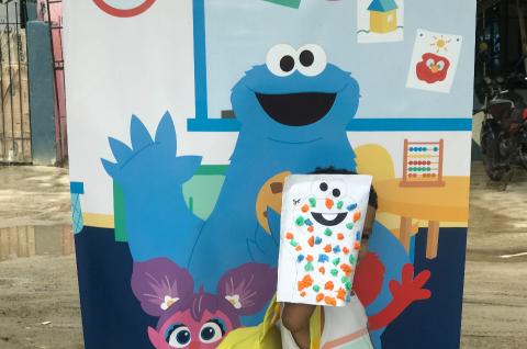 Kid in front of banner with Elmo drawing