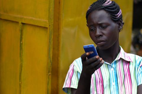 Una fotografía de una mujer sosteniendo y mirando la pantalla de un teléfono móvil.