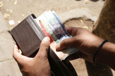 An individual counts Pakistani Ruppe in Karachi, Pakistan  (Photo by Zeeshan Tejani on Unsplash)