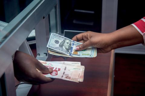 Photo of a teller and customer exchanging bills at a bank