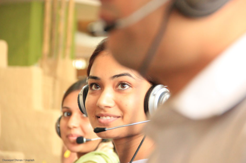 A woman wearing a headset talking in a call center next to her colleagues