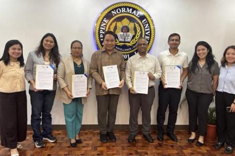 Signatories of the MOU smiling while some of them hold paper copies of the signed MOU