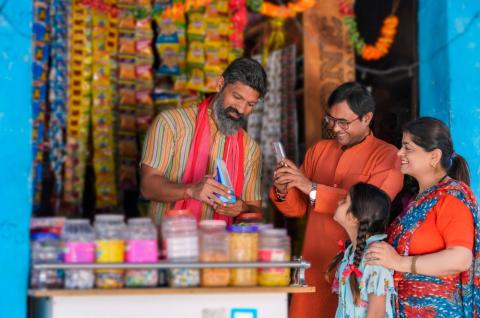Indian rural customer using smartphone for digital payment at groceries shop. © 2023 NIKADS/Shutterstock