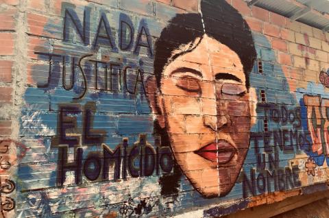 Photo of a mural saying "Nada justifica el homicido" next to an illustration of a persons's face with their eyes closed