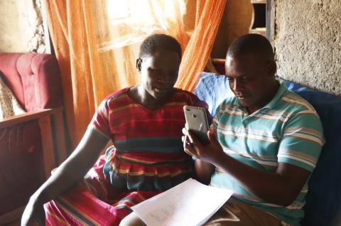 An IPA enumerator (right) shows a faith leader how to use a smartphone for the Becoming One program. © 2018 Aude Guerrucci