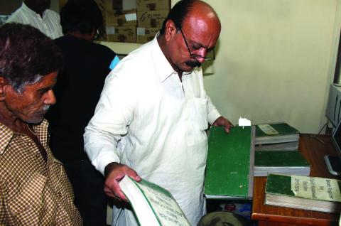 A tax collector reviews documentation from a citizen in Punjab, Pakistan